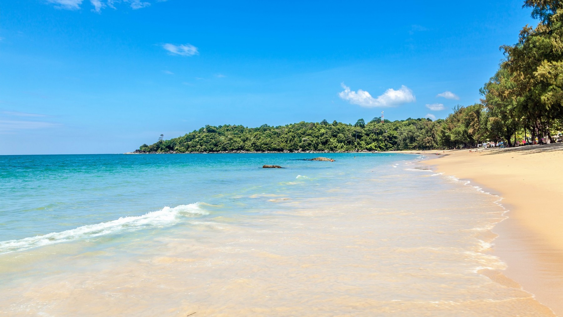 The pristine golden sand of Surin Beach with clear turquoise water.