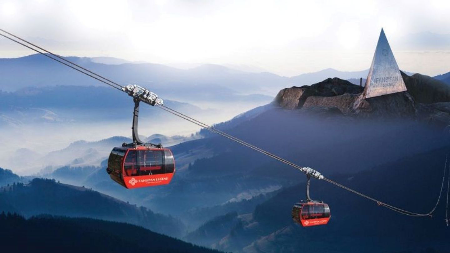 The Fansipan cable car ascending high above the clouds and forested mountains of Sapa, with a view of the peak.